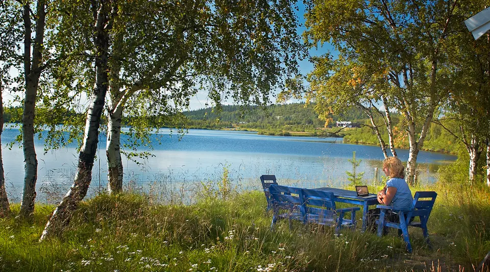 En kvinna som sitter vid ett bord vid en sjö.